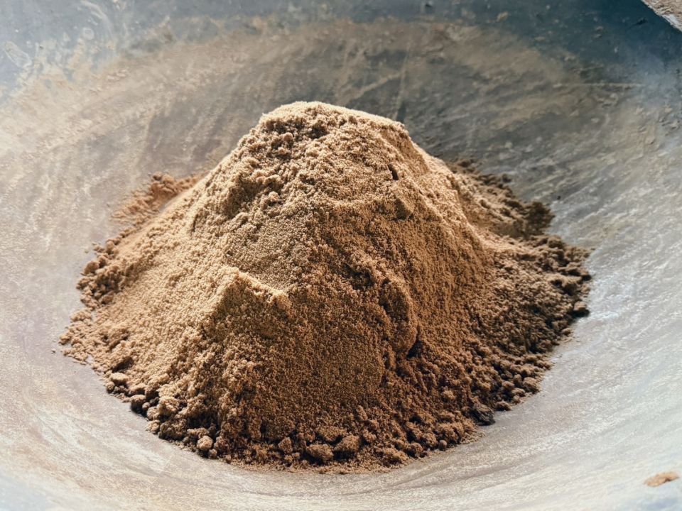 特寫顯示一大堆炒製好的棕色海鹽粉末，堆成一個小山丘的形狀。